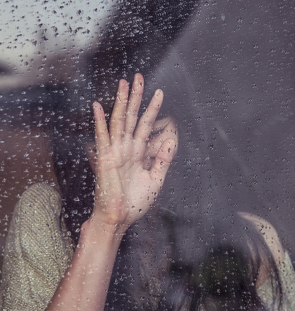 悲しむ女の子と雨の窓